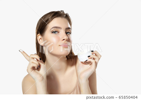 Youth secrets. Close up of beautiful young woman with moisturizer over white background. Cosmetics and makeup, natural and eco treatment, skin care. 65850404