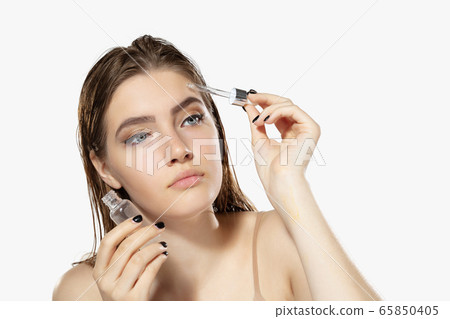 Youth secrets. Close up of beautiful young woman with serum, essential oil over white background. Cosmetics and makeup, natural and eco treatment, skin care. 65850405