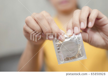 Woman hand holding condom sitting on sofa Woman hand holding condom sitting on sofa 65850928