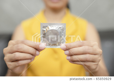 Woman hand holding condom sitting on sofa Woman hand holding condom sitting on sofa 65850929
