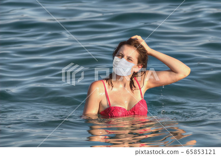 White teen girl in swimsuit stands deep into sea. White teen girl in swimsuit stands deep into sea. 65853121