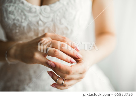 Beautiful luxury bride in elegant white dress holds wedding rings in the hands Beautiful luxury bride in elegant white dress holds wedding rings in the hands 65853756