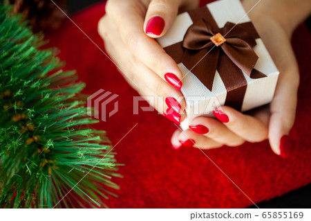 Red Christmas manicure make in beauty studio on Christmas background Red Christmas manicure make in beauty studio on Christmas background 65855169