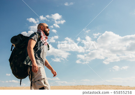 Man with backpack traveling through the desert 65855258