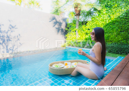 Beautiful young asian women happy smile relax around outdoor swimming pool Beautiful young asian women happy smile relax around outdoor swimming pool 65855796