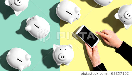 Piggy banks with person using a smartphone Piggy banks with person using a smartphone 65857192