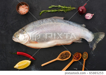 Raw tasmanian ocean trout with spice and herbs on black concrete background Raw tasmanian ocean trout with spice and herbs on black concrete background 65865253