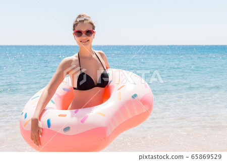 Slim girl in sunglasses inside donut rubber ring Slim girl in sunglasses inside donut rubber ring 65869529