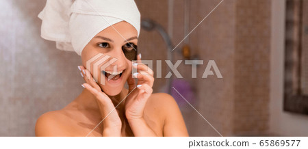 Smiling woman wrapped in a white towel is applying Smiling woman wrapped in a white towel is applying 65869577