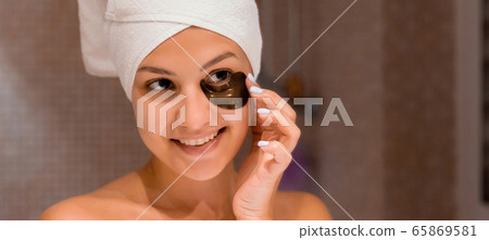 Smiling woman wrapped in a white towel is applying Smiling woman wrapped in a white towel is applying 65869581
