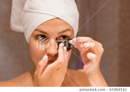 Smiling woman wrapped in a white towel is applying 65869582