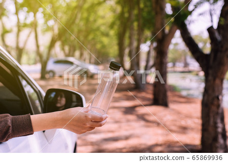 Woman hand holding plastic bottle on the road,Global warming environmental protection concept Woman hand holding plastic bottle on the road,Global warming environmental protection concept 65869936
