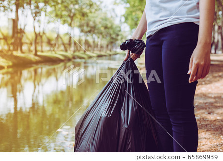 Woman volunteer holding black color garbage bag at park,Dispose plastic recycle and waste management concept,Close up Woman volunteer holding black color garbage bag at park,Dispose plastic recycle and waste management concept,Close up 65869939