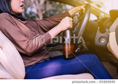 Drunk asian woman drinking alcohol while driving car on road,Women drives her car with a bottle of beer,Dangerous driving concept Drunk asian woman drinking alcohol while driving car on road,Women drives her car with a bottle of beer,Dangerous driving concept 65869940