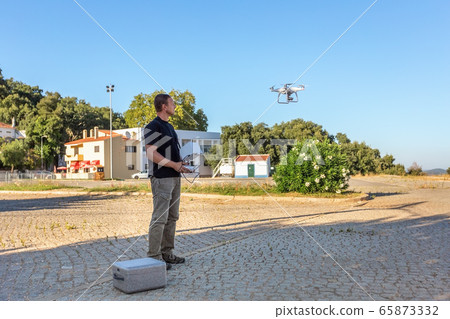 Man, an engineer pilot, prepares air device for take-off, for testing and filming a vileo and photograph. By controlling the remote. Man, an engineer pilot, prepares air device for take-off, for testing and filming a vileo and photograph. By controlling the remote. 65873332