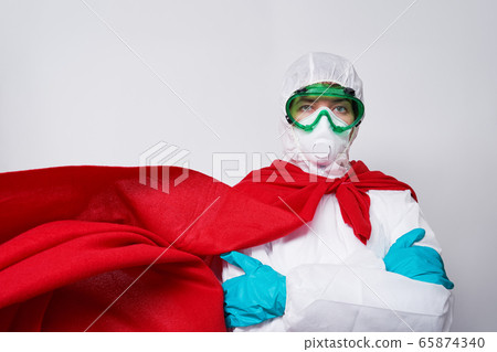 Doctor is wearing PPE - costume, gloves and surgical face mask in superhero cape. Doctor is wearing PPE - costume, gloves and surgical face mask in superhero cape. 65874340