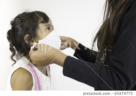 An image of a preschool sister wearing a mask worn by an older sister to prevent germs in the air. 65874773