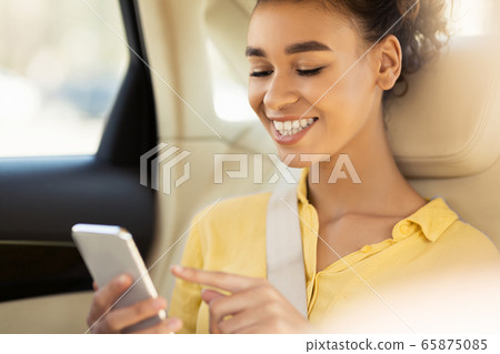 African American Girl Using Smartphone Sitting In Car During Ride 65875085