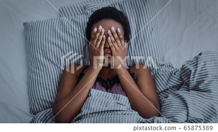African american girl closed eyes with hands in bed African american girl closed eyes with hands in bed 65875389