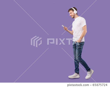 Portrait of young man with headphones using smartphone Portrait of young man with headphones using smartphone 65875724