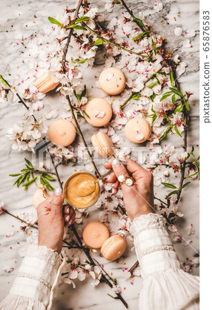Womans hands holding espresso coffee over macaron Womans hands holding espresso coffee over macaron 65876583