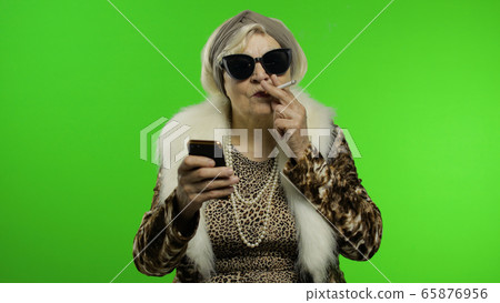 Elderly stylish trendy caucasian grandmother woman using smartphone. Chroma key Elderly stylish trendy caucasian grandmother woman using smartphone. Chroma key 65876956