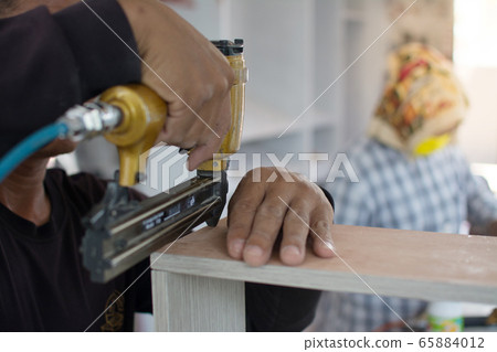 carpenter use air-gun for make new furniture 65884012