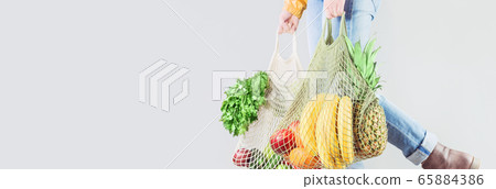 Unrecognizable girl holds two mesh shopper bags 65884386