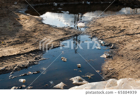 Garbage in the mud on the dirt road. 65884939