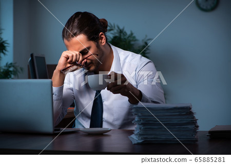 Young male employee working in the office night time 65885281