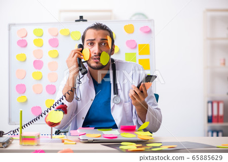 Young male medic in conflicting priorities concept Young male medic in conflicting priorities concept 65885629