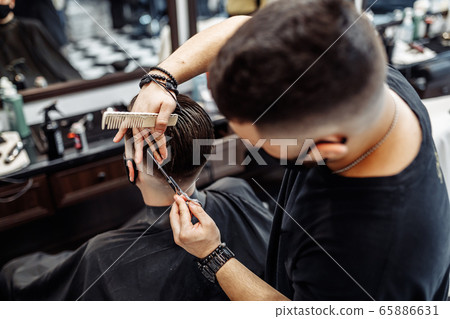 Barber makes a haircut and hair styling in a barbershop, beauty salon.  65886631