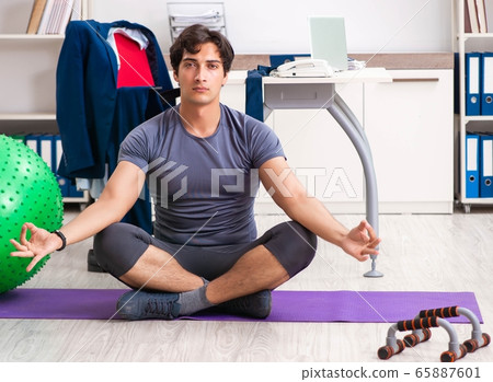 Young male employee exercising in the office Young male employee exercising in the office 65887601