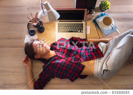 Woman lying down and listening to music on floor Woman lying down and listening to music on floor 65888085