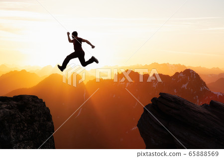Adventure and Challenge Concept Composite of Man Jumping Across a Gap between the Cliffs 65888569