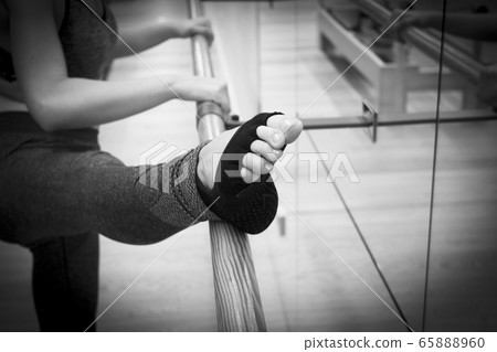 Female dancer doing stretching on the ballet barre 65888960