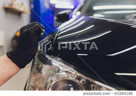 Car detailing - Man applies nano protective coating to the car. Selective focus. 65889186
