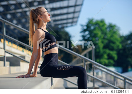 Girl relaxing after workout on stadium at sunrise. Girl relaxing after workout on stadium at sunrise. 65889484