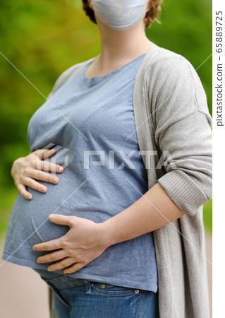 Young pregnant woman wearing protection facemask Young pregnant woman wearing protection facemask 65889725