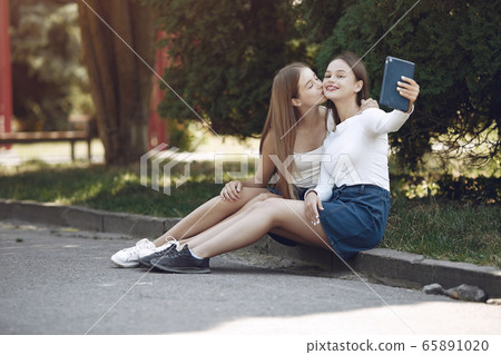 Two elegant and stylish girls in a spring park Two elegant and stylish girls in a spring park 65891020