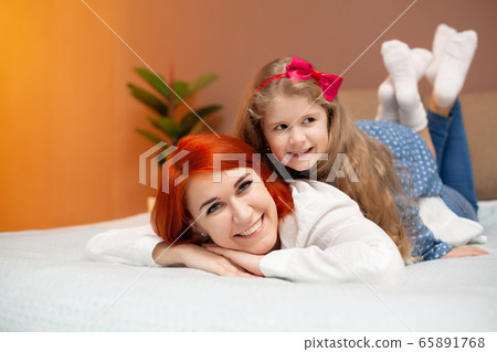 Mother and her baby daughter girl on bed in bedroom. Mother and her baby daughter girl on bed in bedroom. 65891768