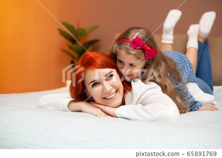 Happy mother and her baby daughter girl on bed in bedroom. Happy mother and her baby daughter girl on bed in bedroom. 65891769