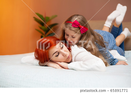 Mother and her baby daughter girl on bed in bedroom. Mother and her baby daughter girl on bed in bedroom. 65891771