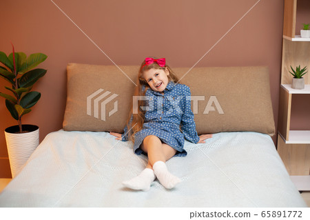 Young girl sitting on bed in the bedroom 65891772