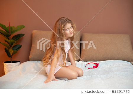 Young girl sitting on bed in the bedroom Young girl sitting on bed in the bedroom 65891775