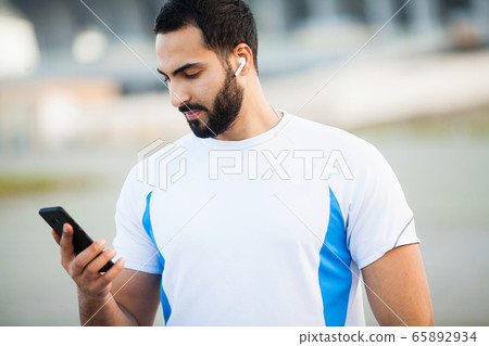 Man after working out in the city park and using his mobile phone Man after working out in the city park and using his mobile phone 65892934