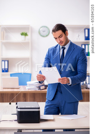 Young male employee making copies at copying machine Young male employee making copies at copying machine 65894103