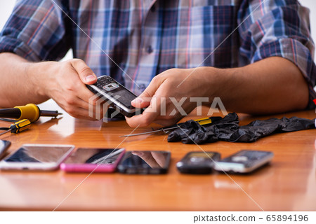 Young male technician repairing mobile phone 65894196