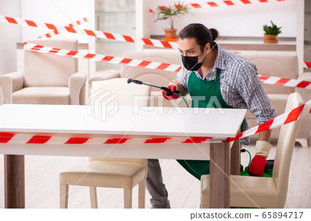 Young male sanitizer disinfecting indoors Young male sanitizer disinfecting indoors 65894717