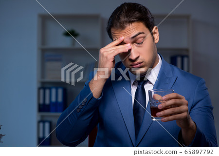 Alcohol addicted businessman working late in the office 65897792